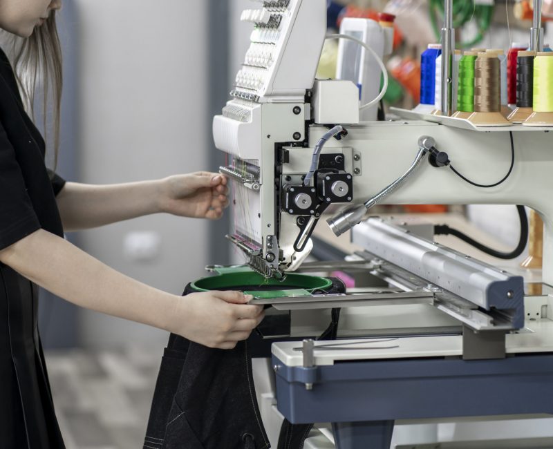 a female worker using and  preparing automatic tailoring machine for work  on clothing manufature factory